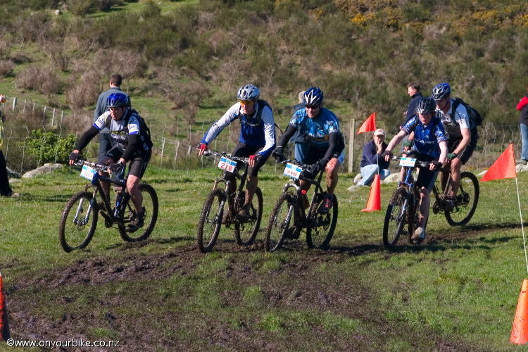 Riders racing through a muddy corner in the Winter Series